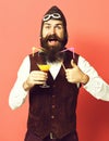 Handsome bearded pilot or aviator man with long beard and mustache on happy face holding glass of alcoholic beverage in Royalty Free Stock Photo