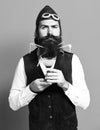 Handsome bearded pilot or aviator man with long beard and mustache on serious face holding glass of alcoholic beverage Royalty Free Stock Photo