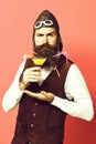 Handsome bearded pilot or aviator man with long beard and mustache on serious face holding glass of alcoholic beverage Royalty Free Stock Photo