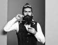 Handsome bearded pilot or aviator man with long beard and mustache on serious face holding glass of alcoholic shot in Royalty Free Stock Photo