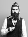 Handsome bearded pilot or aviator man with long beard and mustache on serious face holding glass of alcoholic shot in Royalty Free Stock Photo