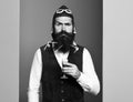 Handsome bearded pilot or aviator man with long beard and mustache on serious face holding glass of alcoholic shot in Royalty Free Stock Photo