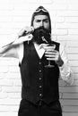 Handsome bearded pilot man with long beard and mustache on serious face holding glass of alcoholic cocktail in vintage Royalty Free Stock Photo