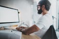 Handsome bearded professional architect wearing eye glasses working at modern loft studio-office with desktop computer