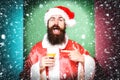 Handsome bearded santa claus man with long beard on funny face holding glass of alcoholic beverage in christmas or xmas