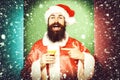 Handsome bearded santa claus man with long beard on smiling face holding glass of alcoholic beverage in christmas or