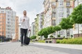 Student walking down street with coffee cup and suitcase. Royalty Free Stock Photo