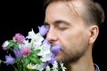 Handsome bearded stylish man sniffs aroma of wild flowers on black background. Gift for my love. Feeling nature concept Royalty Free Stock Photo