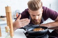 handsome bearded young man in apron cooking delicious steak Royalty Free Stock Photo