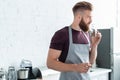 handsome bearded young man in apron holding container with cinnamon sticks