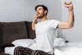 Handsome bearded young man in pajamas stretching while sitting Royalty Free Stock Photo