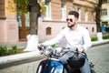 Handsome bearded young man riding blue scooter. Royalty Free Stock Photo