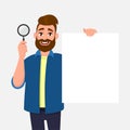 Handsome bearded young man showing/holding magnifying glass and blank/empty poster, paper or sheet in hand. Search, find.