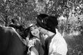 Handsome, beautiful Cowboy and cowgirl couple with horse and saddle on ranch holding and kissing on ranch Royalty Free Stock Photo