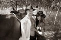 Handsome, beautiful Cowboy and cowgirl couple with horse and saddle on ranch holding and kissing on ranch Royalty Free Stock Photo