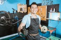 handsome bicycle mechanic in smiling apron holding freewheel with thumb