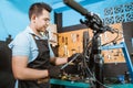 Handsome bicycle mechanic using a high pressure bike pump to adjust shock absorbers