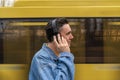 handsome black haired man in blue jeans jacket is standing on the bus stop, waiting for a bus