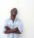 Handsome black man with arms crossed, leaning against white background Royalty Free Stock Photo