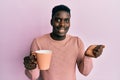 Handsome black man drinking a cup of coffee screaming proud, celebrating victory and success very excited with raised arm Royalty Free Stock Photo