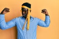 Handsome black man drunk wearing tie over head and sunglasses showing arms muscles smiling proud Royalty Free Stock Photo