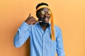 Handsome black man drunk wearing tie over head and sunglasses smiling doing phone gesture with hand and fingers like talking on Royalty Free Stock Photo