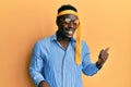 Handsome black man drunk wearing tie over head and sunglasses smiling with happy face looking and pointing to the side with thumb Royalty Free Stock Photo