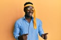 Handsome black man drunk wearing tie over head and sunglasses smiling and looking at the camera pointing with two hands and Royalty Free Stock Photo