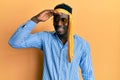 Handsome black man drunk wearing tie over head and sunglasses very happy and smiling looking far away with hand over head Royalty Free Stock Photo