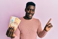 Handsome black man holding 500 philippine peso banknotes smiling happy pointing with hand and finger to the side Royalty Free Stock Photo