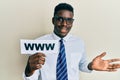 Handsome black man holding www on paper celebrating achievement with happy smile and winner expression with raised hand Royalty Free Stock Photo