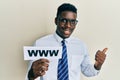 Handsome black man holding www on paper pointing thumb up to the side smiling happy with open mouth Royalty Free Stock Photo