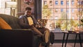 Handsome Black Man Sitting on a Couch and Uses a Laptop Computer in Sunny Stylish Loft Office