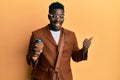 Handsome black man wearing business bag and drinking coffee pointing thumb up to the side smiling happy with open mouth Royalty Free Stock Photo