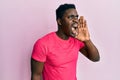 Handsome black man wearing casual pink t shirt shouting and screaming loud to side with hand on mouth Royalty Free Stock Photo
