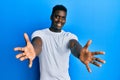 Handsome black man wearing casual white t shirt looking at the camera smiling with open arms for hug Royalty Free Stock Photo
