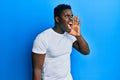 Handsome black man wearing casual white t shirt shouting and screaming loud to side with hand on mouth Royalty Free Stock Photo