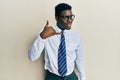 Handsome black man wearing glasses business shirt and tie smiling doing phone gesture with hand and fingers like talking on the Royalty Free Stock Photo