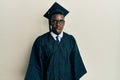 Handsome black man wearing graduation cap and ceremony robe afraid and shocked with surprise and amazed expression, fear and Royalty Free Stock Photo