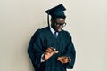 Handsome black man wearing graduation cap and ceremony robe disgusted expression, displeased and fearful doing disgust face Royalty Free Stock Photo