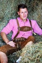 Handsome blond bavarian man sitting in hay Royalty Free Stock Photo
