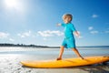 Cute blond boy stand on the surfboard learning balance at beach Royalty Free Stock Photo