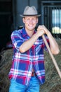 Blond man at a barn holdiing pitchfork