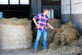 Blond man at a barn holdiing pitchfork with hay Royalty Free Stock Photo