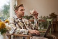 Handsome blond man with laptop, sitting in cafe and drinking coffee, working online, freelancing, set up workspace Royalty Free Stock Photo