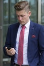 Handsome blond man in suit standing outside with his phone Royalty Free Stock Photo