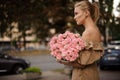 Handsome woman gently holds bouquet with pink flowers and looks away Royalty Free Stock Photo