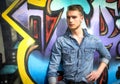 Handsome blond young man against colorful graffiti wall