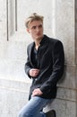 Handsome blond young man leaning against white wall Royalty Free Stock Photo