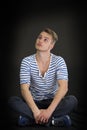 Handsome blond young man sitting on black background